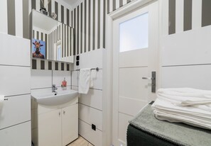 Un bagno moderno con lavandino bianco, specchio e motivo a righe sulle pareti.