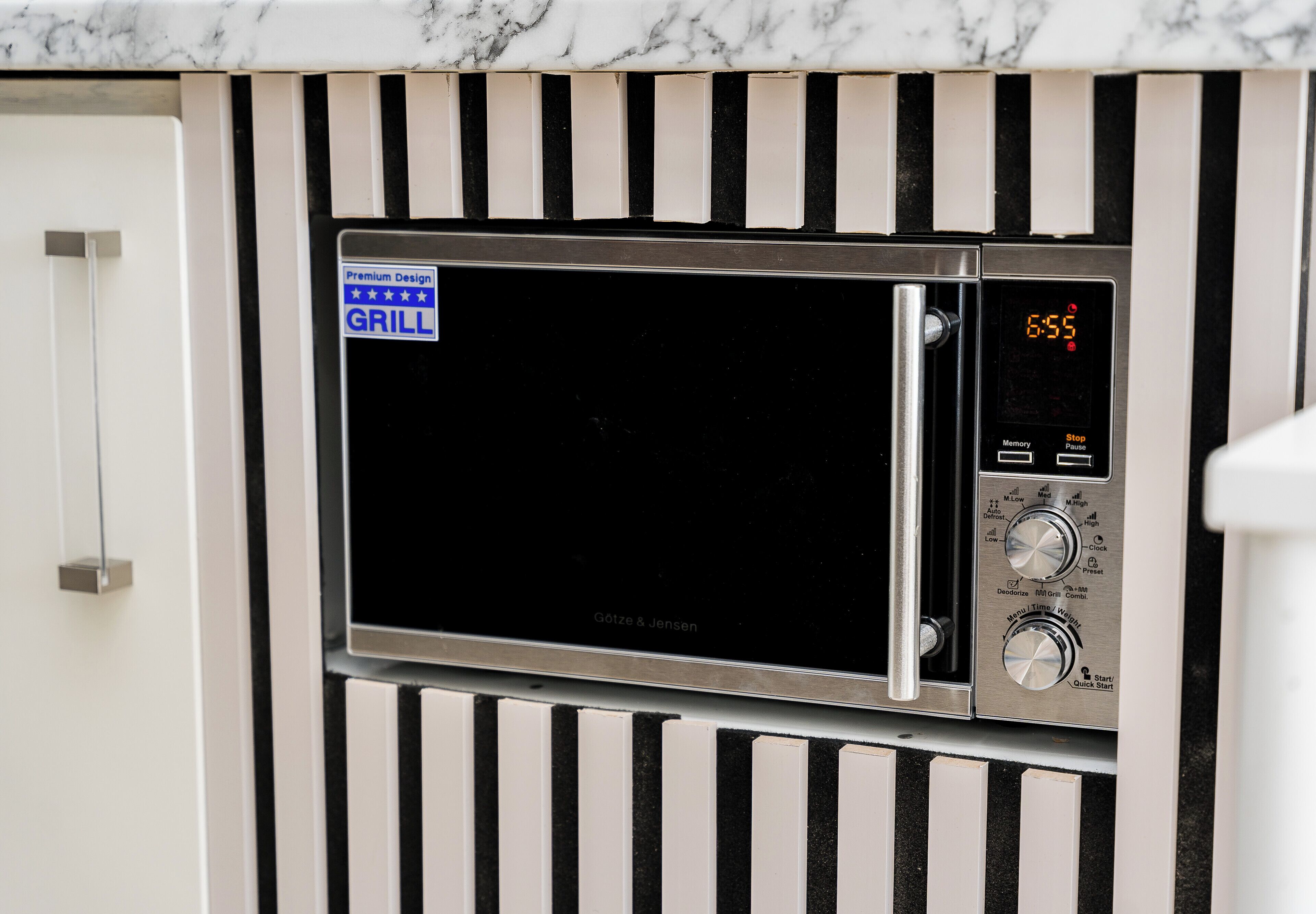 Een rvs magnetronoven met een digitaal display, bedieningsknoppen en een 'Premium Design GRILL' label.