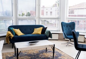 Ein modernes Wohnzimmer mit einem blauen Sofa, einem passenden Sessel und einem weißen Couchtisch.