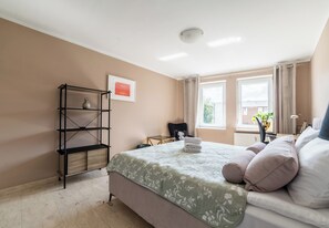 Una camera da letto con un letto, un mobile contenitore, una finestra e un termosifone.