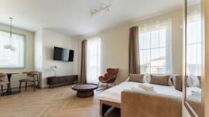 A modern hotel room with a bed, seating area, TV, and large windows. - Ogrody Tesoro 52 Apartment (Pogórze)