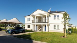 A two-story building with a covered entrance and a staircase leading to the upper floor. - Ogrody Tesoro 52 Apartment (Pogórze)