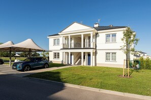A two-story building with a covered entrance and a staircase leading to the upper floor. - Ogrody Tesoro 52 Apartment (Pogórze)