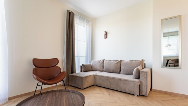 A modern living room with a brown leather chair, a beige sofa, and a wooden coffee table. - Ogrody Tesoro 52 Apartment (Pogórze)