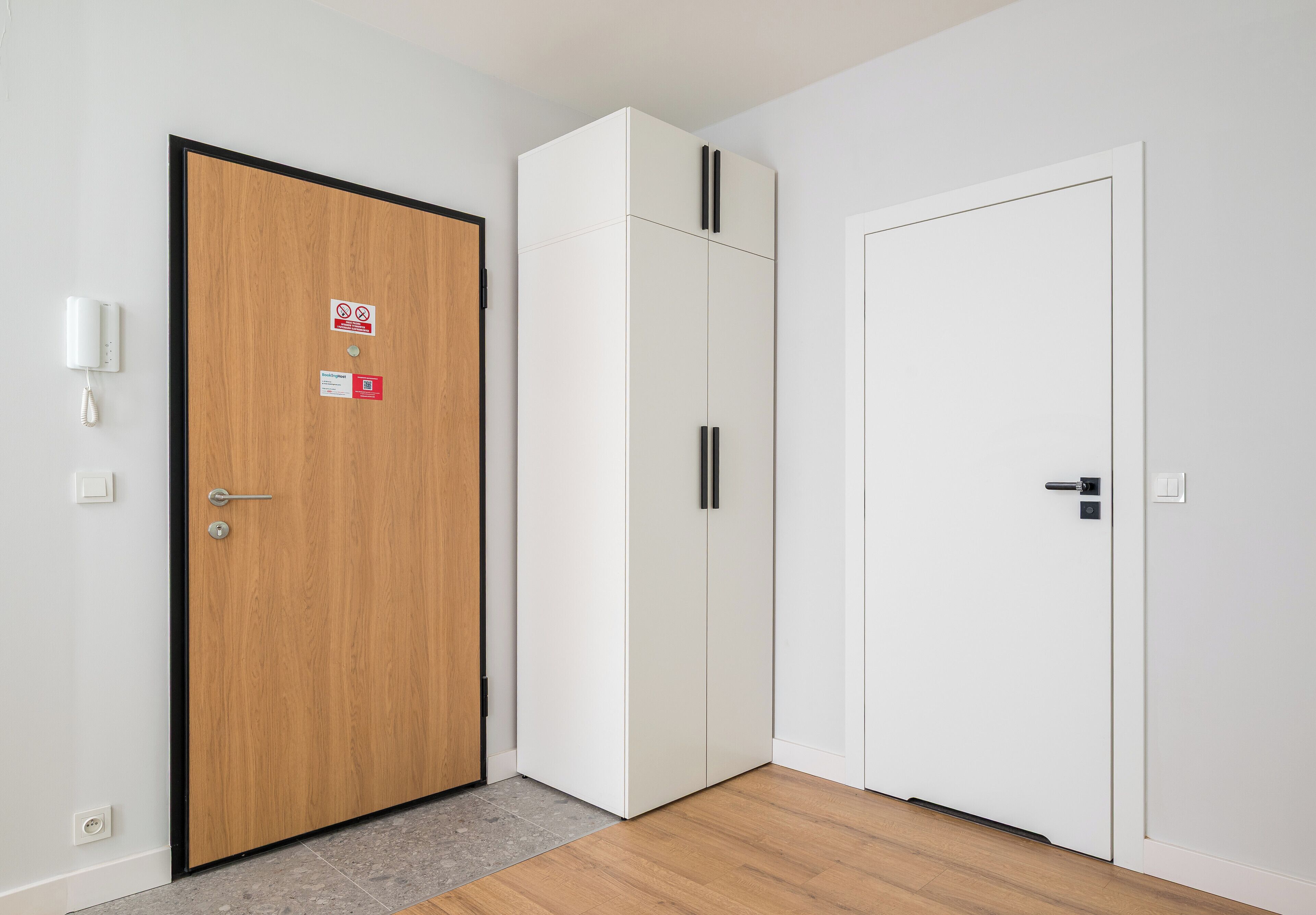 Ein Zimmer mit einer Holztür, einem weißen Wandschrank und einem weißen Kleiderschrank.