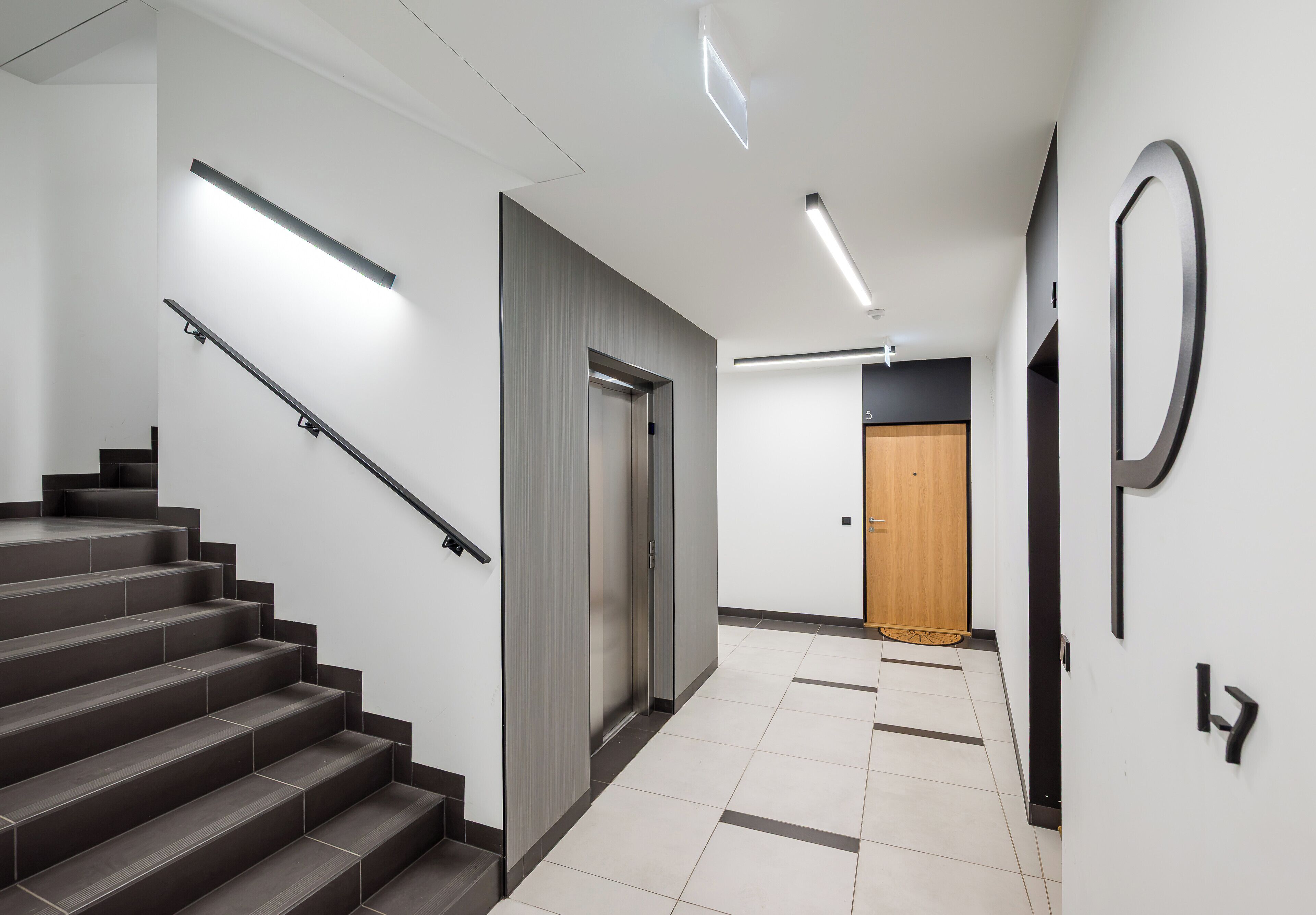 Ein modernes Interieur mit einer Treppe, einer Tür und einer Wandleuchte.