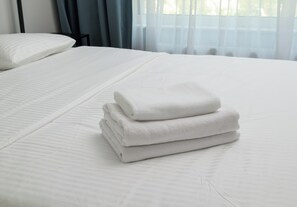 A neatly made bed with white linens and a stack of folded towels. - Warszawa Zacisze-Wilno Deluxe Apartment (Warszawa)