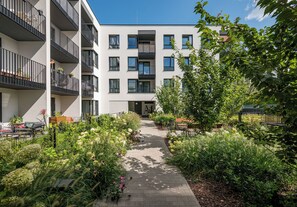 A multi-story residential building with balconies, a paved pathway, and lush greenery. - Warszawa Zacisze-Wilno Deluxe Apartment (Warszawa)