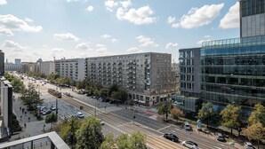 Una calle urbana con edificios modernos, un tranvía y un cielo despejado.