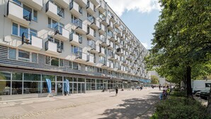 Un edificio de varios pisos con una fila de balcones, un café y una acera para peatones.