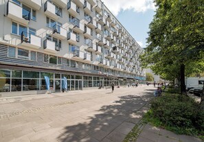 A multi-story building with a row of balconies, a cafe, and a pedestrian walkway. - Marszałkowska City View Apartment (Warszawa)