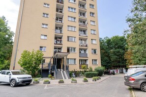 En flervåningsbyggnad med bostäder, en central entré, balkonger och en parkeringsplats.