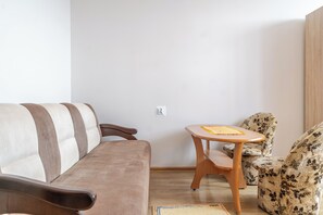 Una sala de estar con un sofá, una mesita y un sillón estampado.