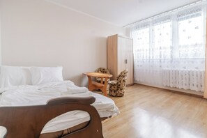Ett hotellrum med en säng, en trästol, ett litet bord och en garderob.
