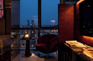 A high-rise room with a city view, a red chair, a table with a candle, and a book. - Aranciel (Chongqing)