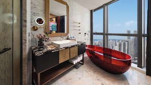Une salle de bain moderne avec un grand miroir, un meuble-lavabo et une baignoire rouge.