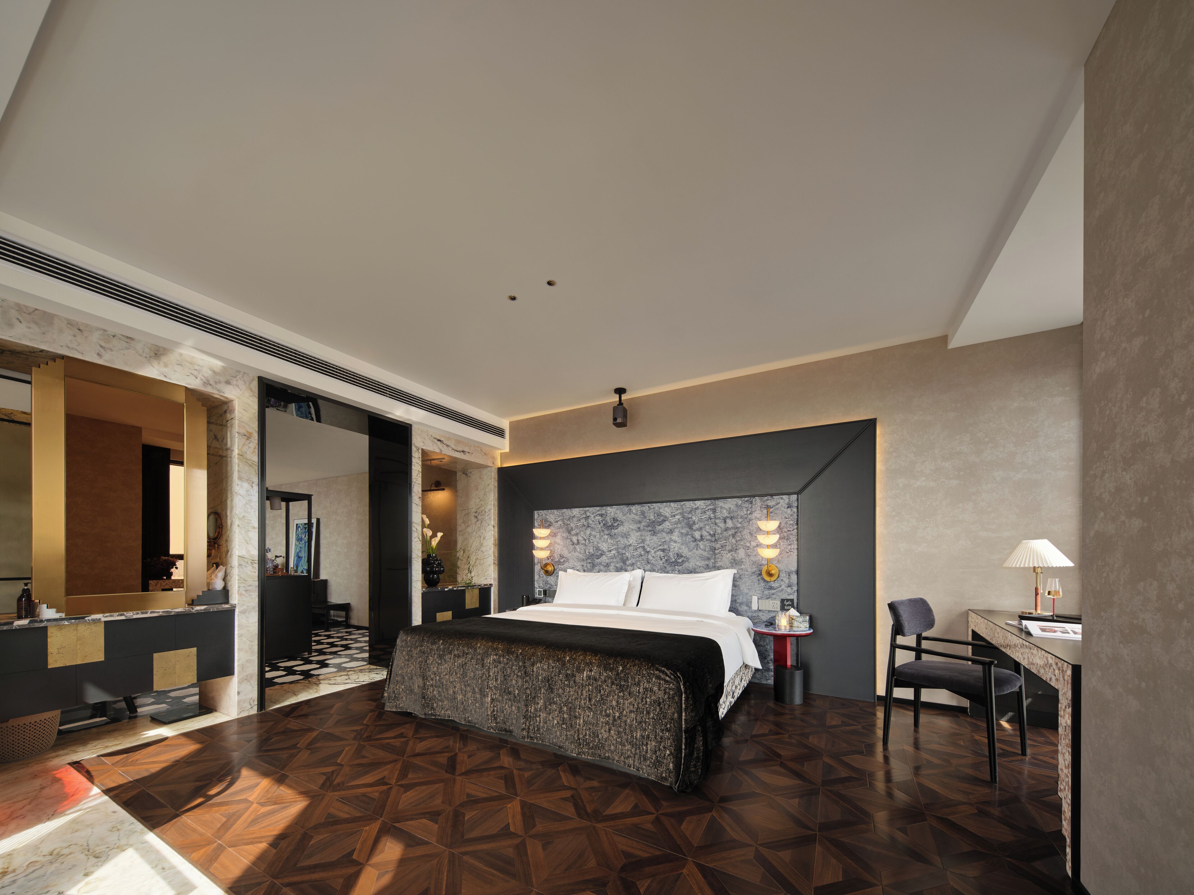 A modern hotel room with a large bed, a desk, and a chair.