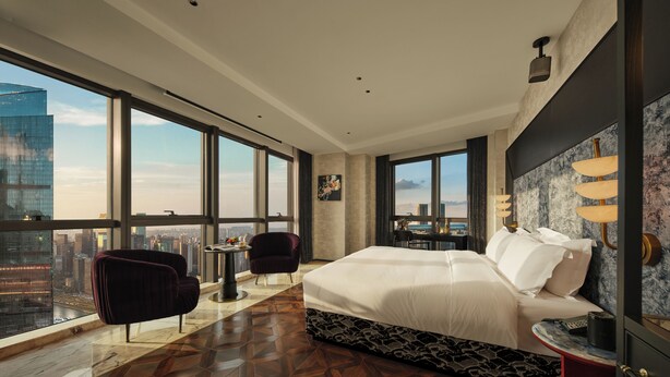 Une chambre d’hôtel moderne dotée d’un grand lit, d’un coin salon et offrant une vue sur le paysage urbain.