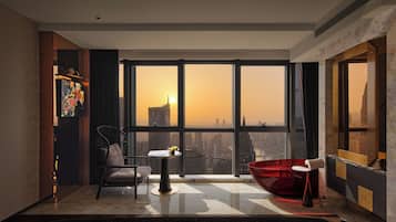 A modern interior with a large window, a red chair, a small table, and a city view.