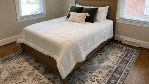 Ein Schlafzimmer mit einem Bett, einem Deckenventilator und einem gemusterten Teppich.