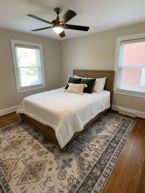 A bedroom with a bed, a ceiling fan, and a patterned rug. - Charming Historic Bungalow in Emerywood - High Point's Sought-After Neighborhood (High Point)