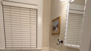 Ein Badezimmer mit Toilette, Waschbecken und einem Fenster mit Jalousien.