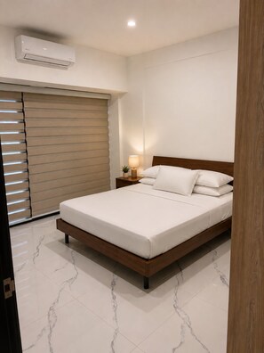 A bedroom with a bed, bedside table, lamp, air conditioning unit, and a sliding door. - Enjoyable 1-bedroom apartment with AC in lovely Oranjestad (Oranjestad)