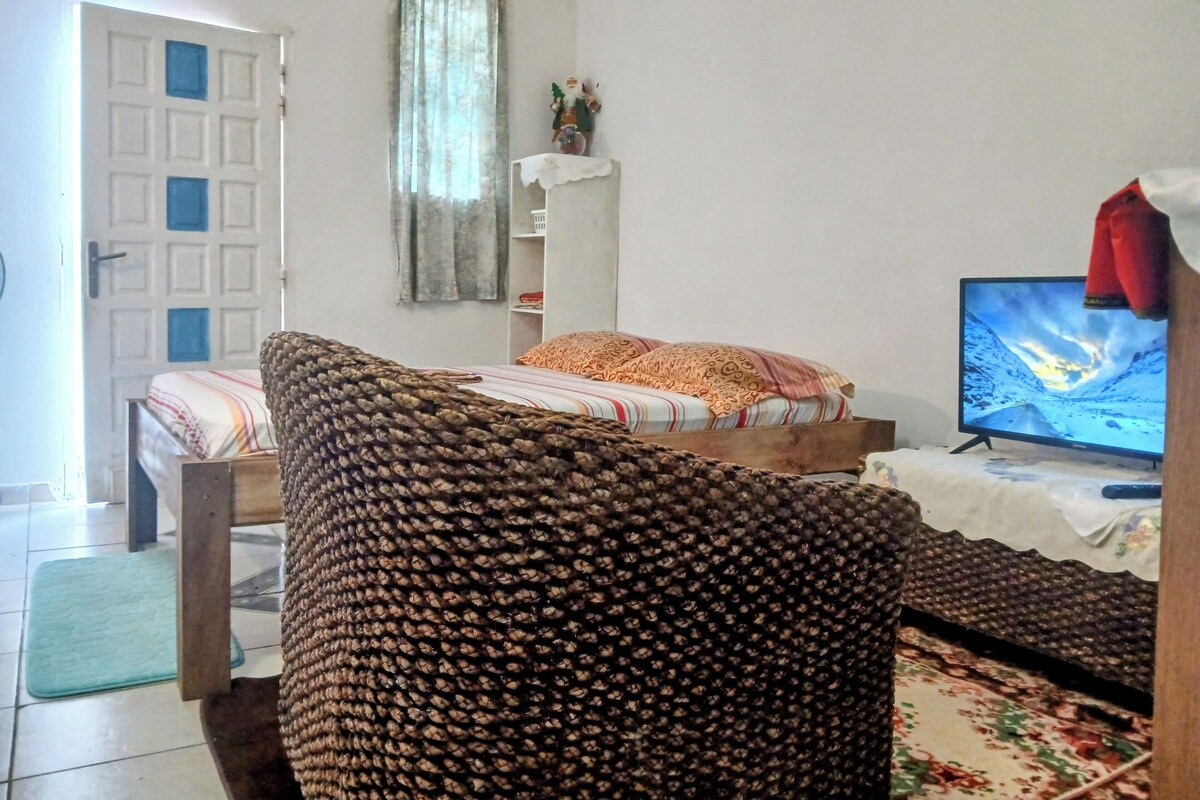 A room with a bed, a television, and a window with curtains.