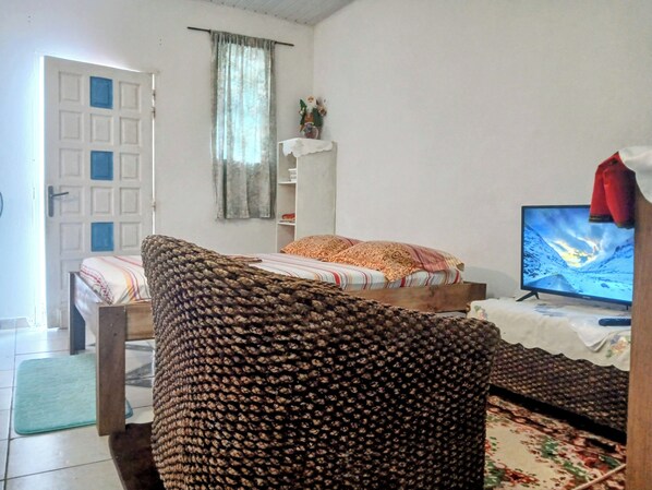A room with a bed, a television, and a window with curtains. - LE MILANO (Kourou)