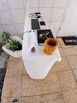 A table with a laptop, keys, a notebook, and a plant.