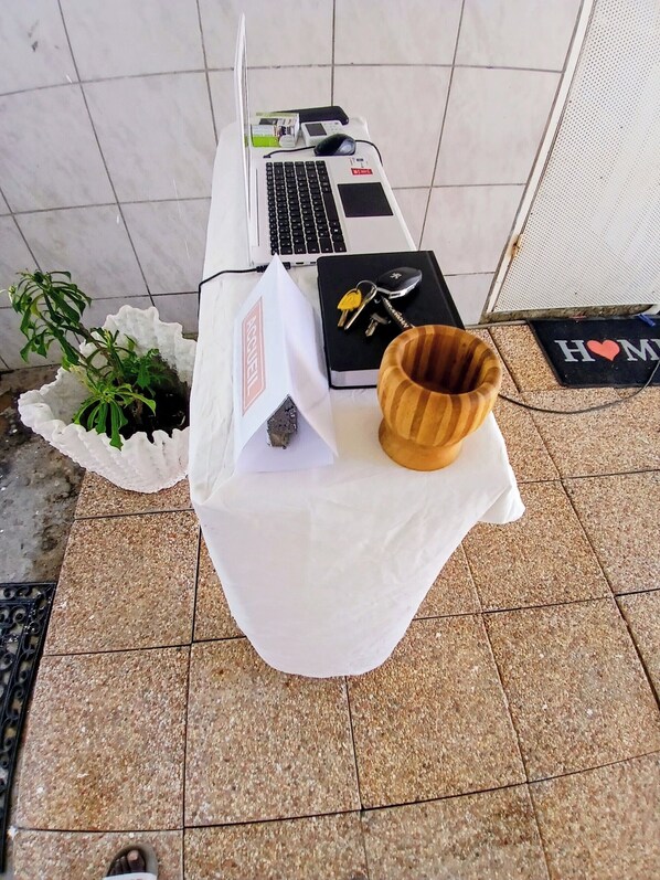 A table with a laptop, keys, a notebook, and a plant.
