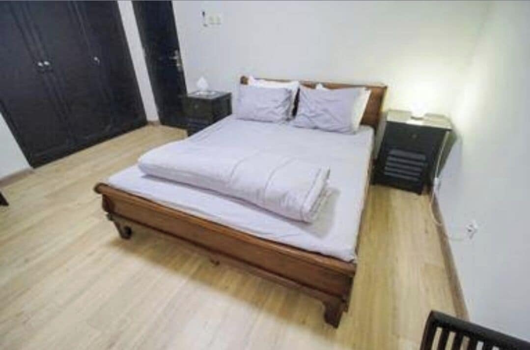 A bedroom with a wooden bed, a nightstand, and a wall-mounted heater.