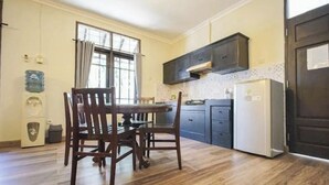 Uma cozinha com mesa de jantar, cadeiras, armários, geladeira e bebedouro.