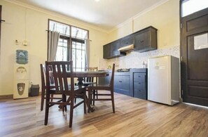 Una cocina con una mesa de comedor, sillas, armarios, un refrigerador y un dispensador de agua.