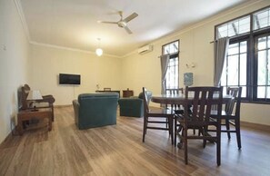 Amplia sala de estar con mesa de comedor, sillas, sofá, televisor y ventilador de techo.