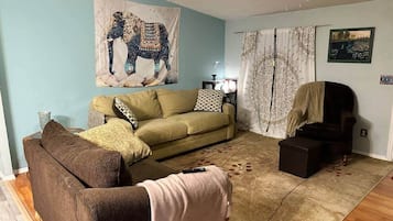 Uma sala de estar com um sofá, uma poltrona, um tapete e um tapeçaria na parede.