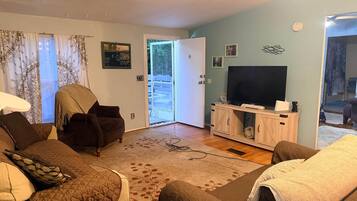 Un salon comprenant un canapé, un fauteuil et un téléviseur posé sur un meuble en bois.