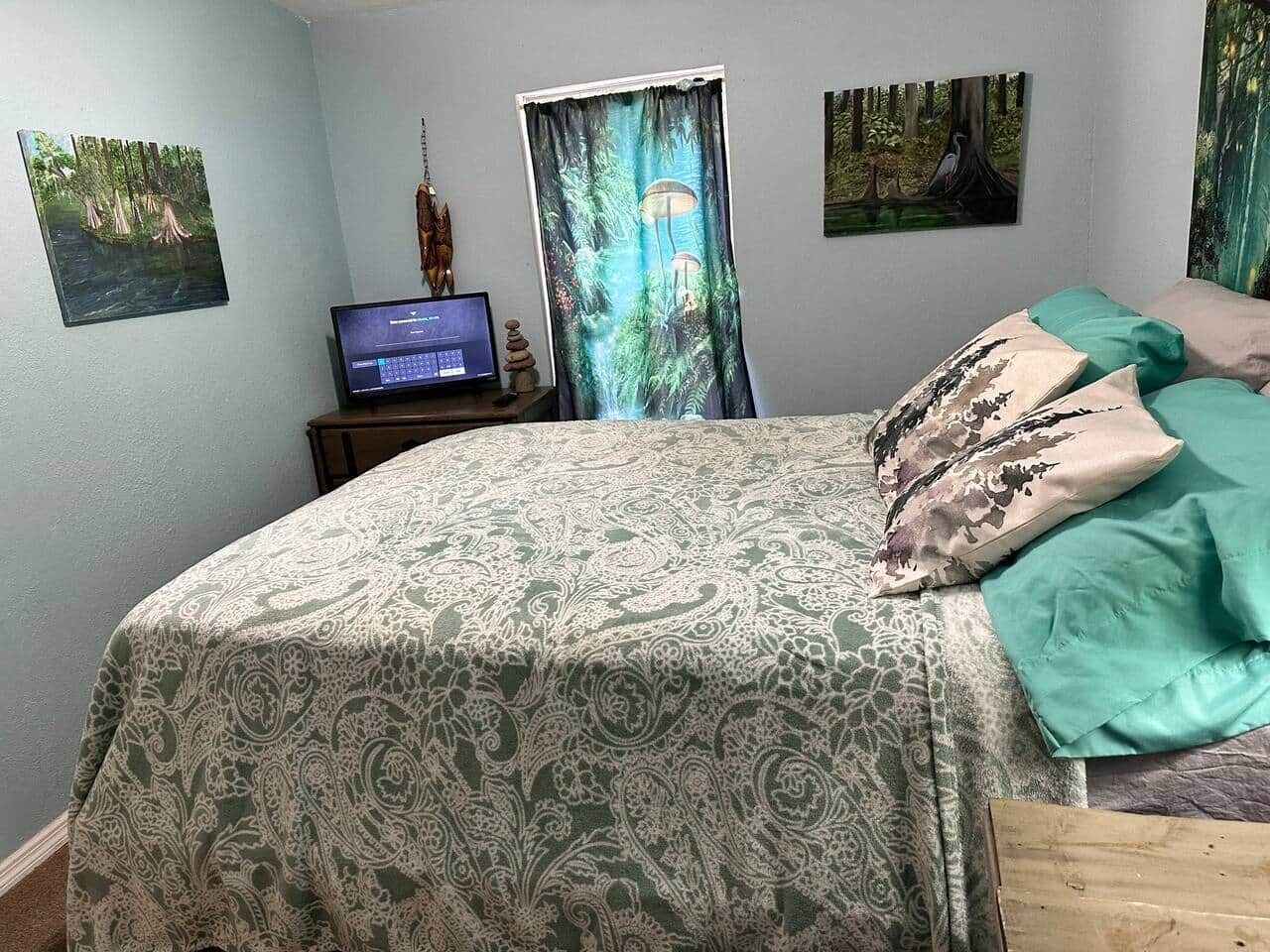 Un dormitorio con una cama, un escritorio con una computadora y tres cuadros en la pared.