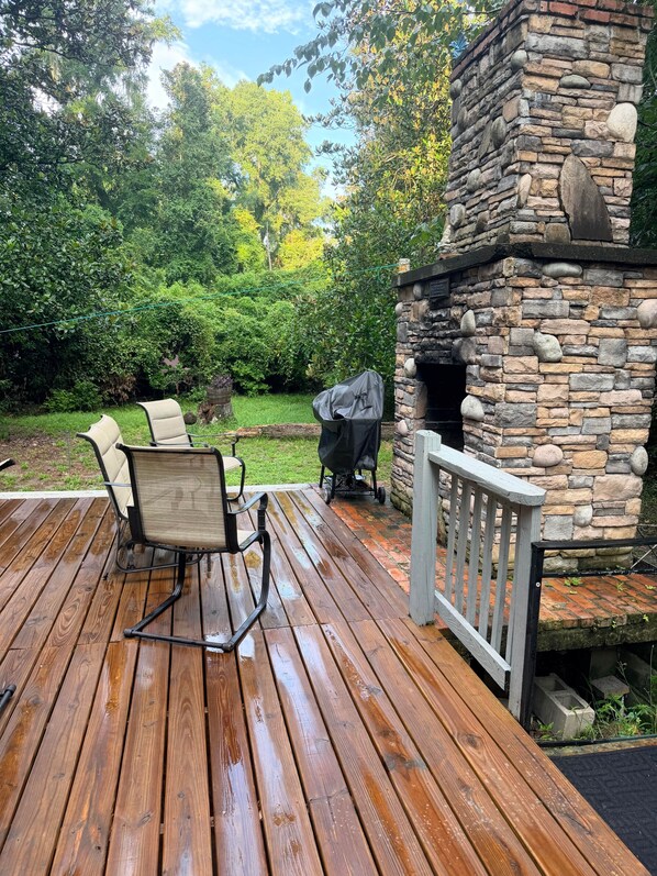 A wooden deck with outdoor furniture, a stone fireplace, and a view of a lush garden. - 3 Rivers Crystal Cabin 3/2 Nature Lovers Only -Spring Access (Columbia County)