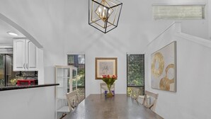 A dining area with a wooden table, chairs, a vase of flowers, and artwork on the walls. - Stylish 2BR Near Bellevue & Kirkland w/ Pool+AC (Bellevue)