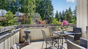A balcony with outdoor furniture, a grill, and a potted plant. - Stylish 2BR Near Bellevue & Kirkland w/ Pool+AC (Bellevue)
