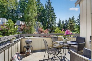Een balkon met buitenmeubilair, een barbecue en een bloempot.