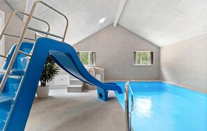 Ein Hallenbad mit einer blauen Rutsche, einer Leiter und einem Blumentopf.