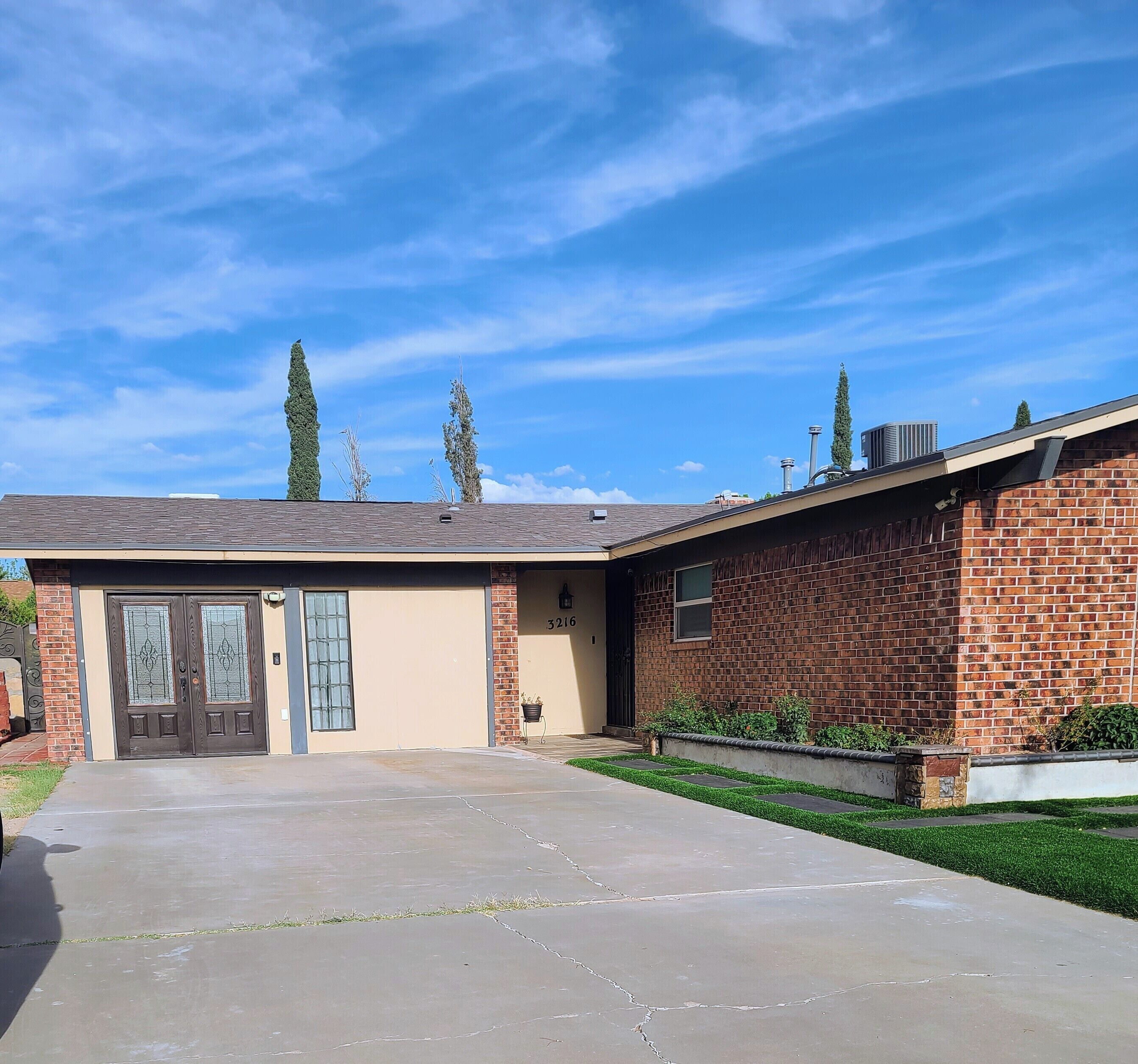 A residential building with a garage, a brick exterior, and a clear sky.