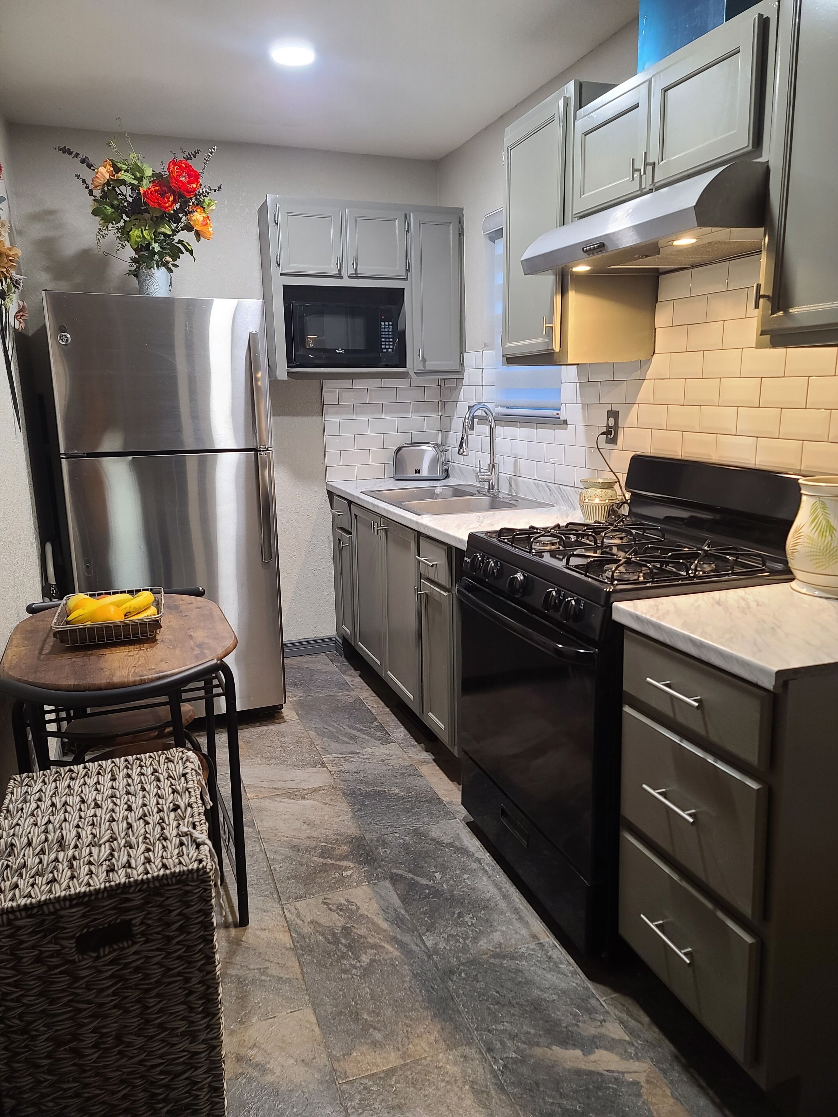 A modern kitchen with stainless steel appliances, a microwave, a gas stove, and a sink.