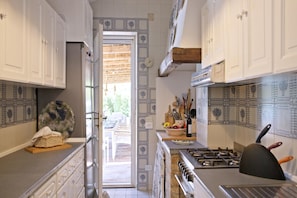 Una cocina con gabinetes blancos, una estufa y un comedor con mesa y sillas.