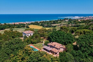 Um imóvel à beira-mar com piscina, rodeado por vegetação exuberante e vista para o mar.