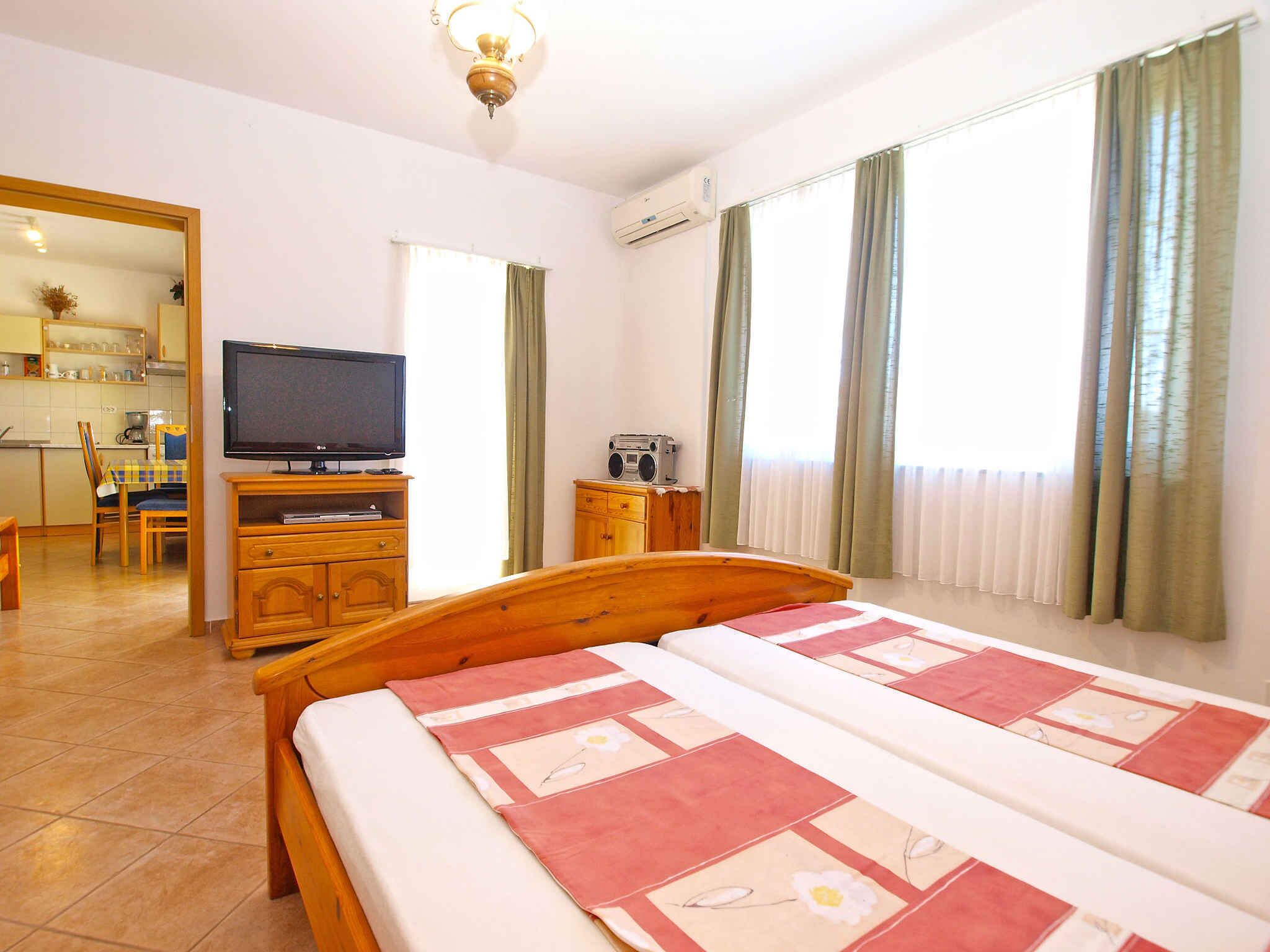 Ein Schlafzimmer mit Bett, Fernseher, Küchenzeile und Bad.
