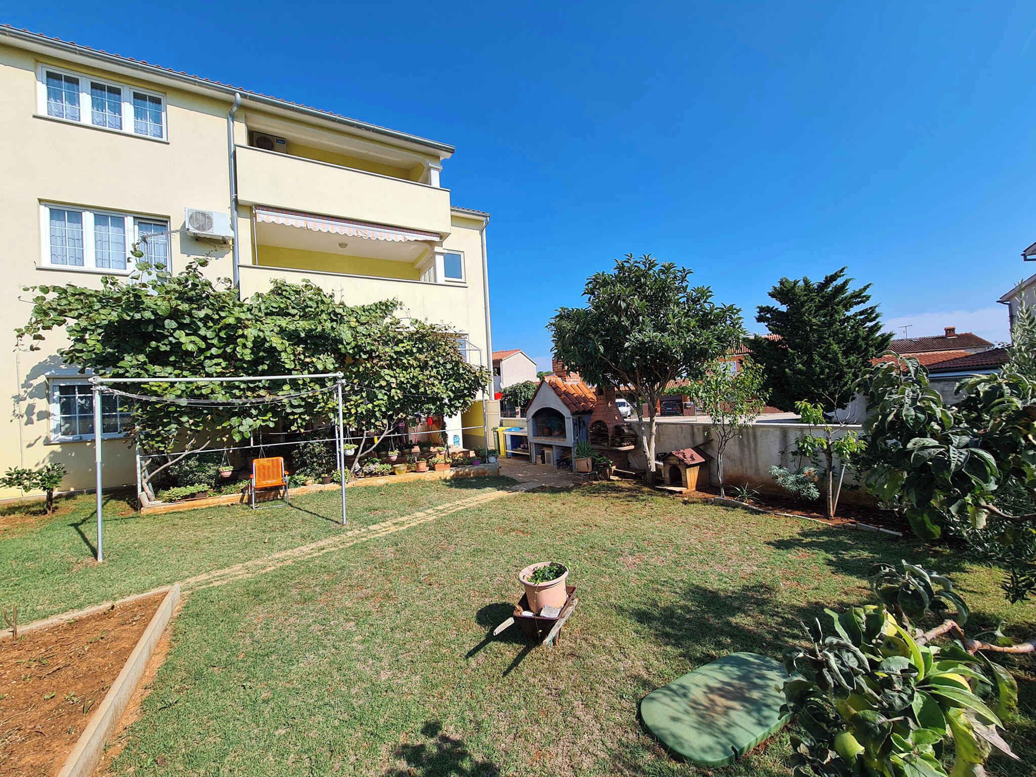 Un quartier résidentiel avec une pelouse bien entretenue, une balançoire et une petite niche pour chien.
