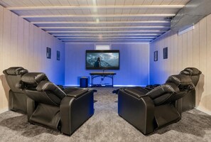 Een bioscoopzaal met twee leren fauteuils, een grote flatscreen televisie en een geluidsinstallatie.